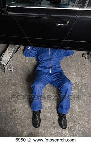 Stock Image - A car mechanic servicing a car. Fotosearch