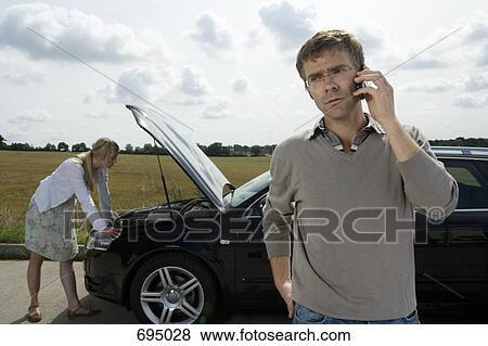 A couple standing at the roadside next to their broken down car View Large Photo Image Stock Photo - A couple standing at the roadside next to their broken down car. Fotosearch
