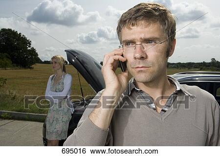 A couple standing at the roadside next to their broken down car View Large Photo Image Stock Photograph - A couple standing at the roadside next to their broken down car. Fotosearch