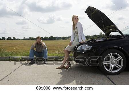 A couple waiting at the roadside for assistance with their car View Large Photo Image Stock Photo - A couple waiting at the roadside for assistance with their car. Fotosearch
