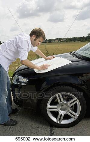 A man leaning on a car bonnet and reading a map View Large Photo Image Stock Image - A man leaning on a car bonnet and reading a map. Fotosearch