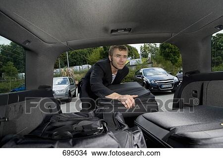 A man loading luggage into the boot of a car View Large Photo Image Picture - A man loading luggage into the boot of a car. Fotosearch