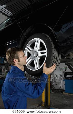 A mechanic fixing the wheel of a car in a repair garage View Large Photo Image Stock Photo - A mechanic fixing the wheel of a car in a repair garage. Fotosearch