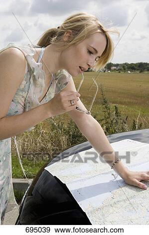 A woman leaning on a car bonnet and reading a map View Large Photo Image Stock Photo - A woman leaning on a car bonnet and reading a map. Fotosearch