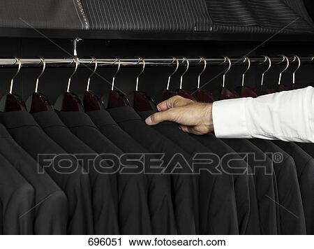 A man selecting a jacket from a clothing rack View Large Photo Image Stock Image - A man selecting a jacket from a clothing rack. Fotosearch