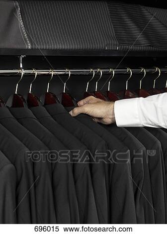 Stock Photography - A man selecting a jacket from a clothing rail. Fotosearch