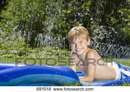 A boy lying on a water slide View Large Photo Image Stock Photo - A boy lying on a water slide. Fotosearch
