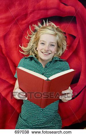 A girl lying on a blanket and reading a book View Large Photo Image Stock Photo - A girl lying on a blanket and reading a book. Fotosearch