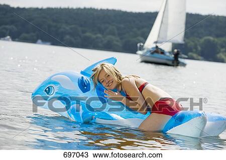 A girl lying on an pool raft on a lake View Large Photo Image Stock Image - A girl lying on an pool raft on a lake. Fotosearch