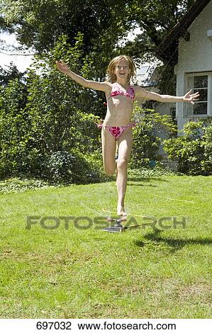 A girl running through a sprinkler View Large Photo Image Stock Image - A girl running through a sprinkler. Fotosearch