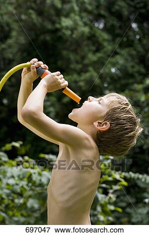 A young boy catching the last drop of water from a garden hose View Large Photo Image Stock Photo - A young boy catching the last drop of water from a garden hose. Fotosearch