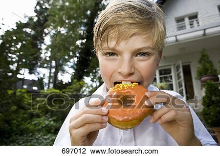 Stock Image - A young boy eating a donut. Fotosearch