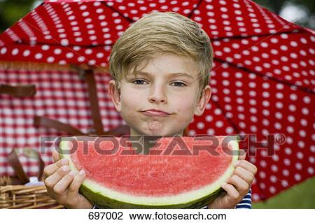 A young boy holding a slice of watermelon with a bite missing View Large Photo Image Stock Image - A young boy holding a slice of watermelon with a bite missing. Fotosearch