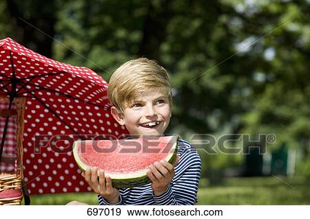A young boy holding a slice of watermelon View Large Photo Image Stock Photo - A young boy holding a slice of watermelon. Fotosearch
