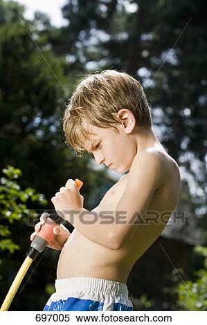 Stock Photography - A young boy looking into the end of garden hose. Fotosearch