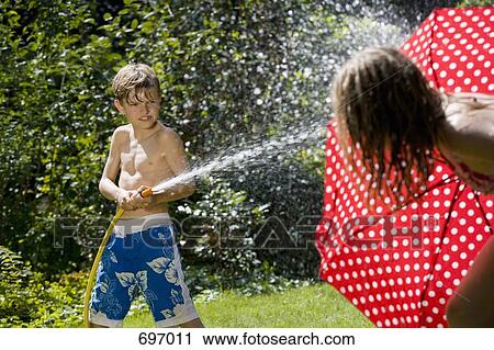 A young boy spraying at his sister with a garden hose View Large Photo Image Stock Image - A young boy spraying at his sister with a garden hose. Fotosearch