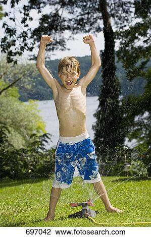 A young boy standing in a sprinkler View Large Photo Image Stock Image - A young boy standing in a sprinkler. Fotosearch