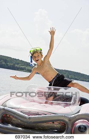 A young boy standing in an inflatable raft on a lake View Large Photo Image Picture - A young boy standing in an inflatable raft on a lake. Fotosearch