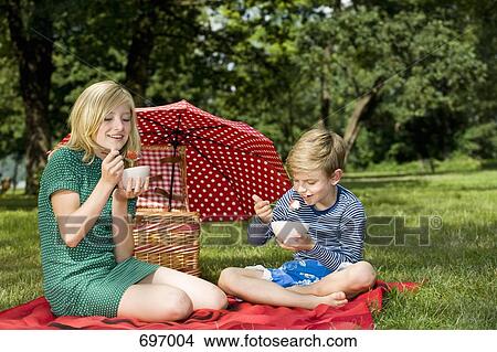 Two children eating strawberries and yogurt at a picnic View Large Photo Image Picture - Two children eating strawberries and yogurt at a picnic. Fotosearch