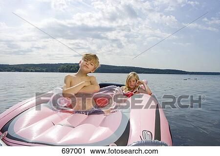Stock Image - Two children in an inflatable raft on a lake. Fotosearch