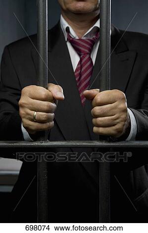 A business man standing behind prison cell bars View Large Photo Image Picture - A business man standing behind prison cell bars. Fotosearch