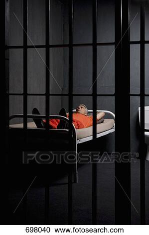 A prisoner lying on his bed in a prison cell View Large Photo Image Stock Image - A prisoner lying on his bed in a prison cell. Fotosearch