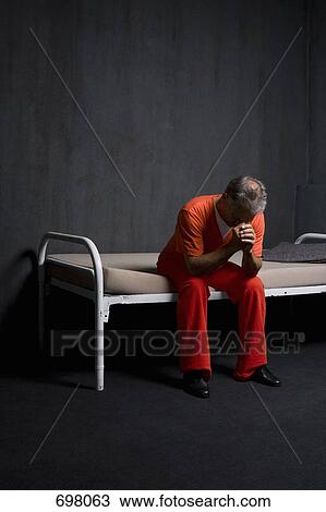 Stock Image - A prisoner sitting in his prison cell. Fotosearch