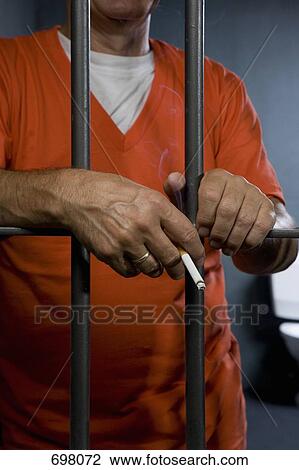 A prisoner smoking a cigarette in his prison cell View Large Photo Image Stock Image - A prisoner smoking a cigarette in his prison cell. Fotosearch