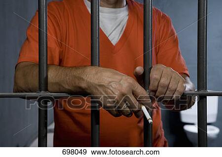 Stock Photo - A prisoner smoking a cigarette in his prison cell. Fotosearch