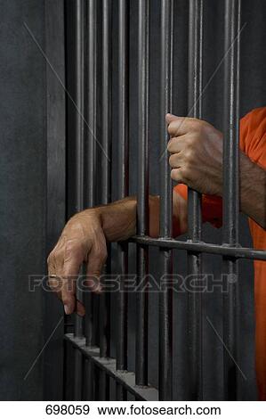 A prisoner standing behind his prison cell bars View Large Photo Image Stock Photo - A prisoner standing behind his prison cell bars. Fotosearch