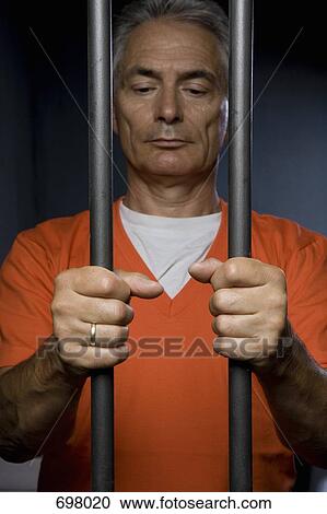 A prisoner standing behind prison bars View Large Photo Image Stock Image - A prisoner standing behind prison bars. Fotosearch