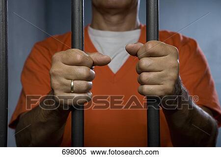 A prisoner standing behind prison bars View Large Photo Image Stock Photography - A prisoner standing behind prison bars. Fotosearch
