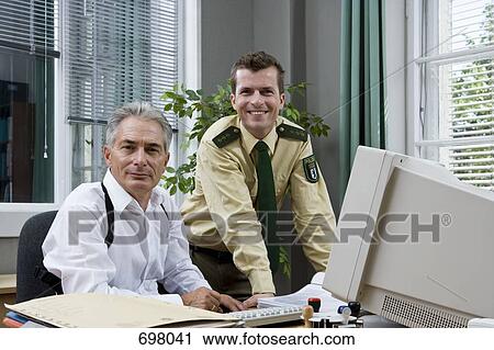 Stock Image - Two police officers working in an office. Fotosearch