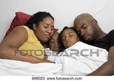 Stock Image - A family four sleeping in bed together. Fotosearch