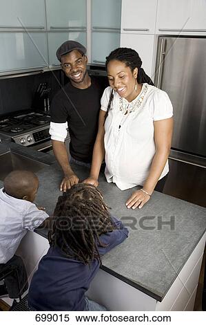 Stock Photography - A family of four talking in a domestic kitchen. Fotosearch