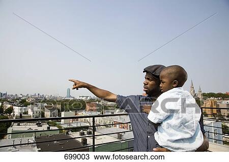 A father holding his son on a balcony View Large Photo Image Stock Image - A father holding his son on a balcony. Fotosearch