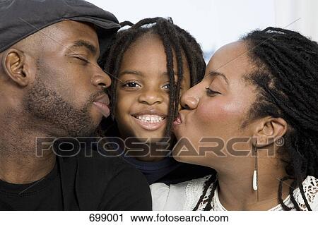 Stock Image - A mother and father kissing their son on the cheek. Fotosearch