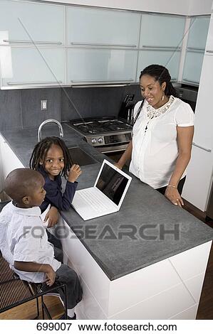 Stock Photo - A mother and her two sons in a domestic kitchen. Fotosearch