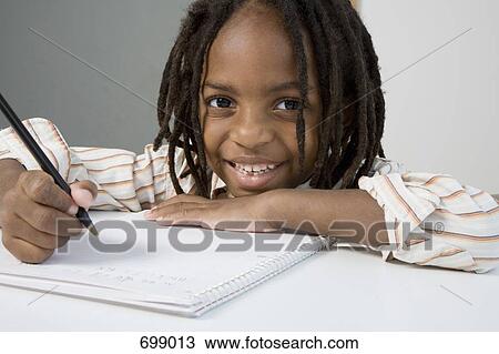 Stock Image - A young boy doing his homework. Fotosearch