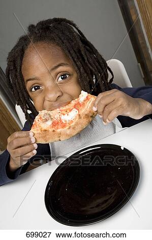 A young boy eating a slice of pizza View Large Photo Image Stock Photo - A young boy eating a slice of pizza. Fotosearch