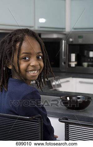 Stock Image - A young boy sitting at a kitchen counter. Fotosearch