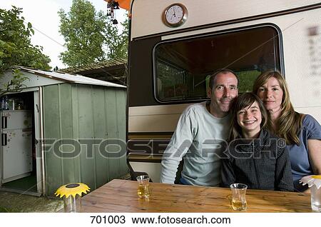 A family sitting at a table outside of their caravan View Large Photo Image Stock Image - A family sitting at a table outside of their caravan. Fotosearch