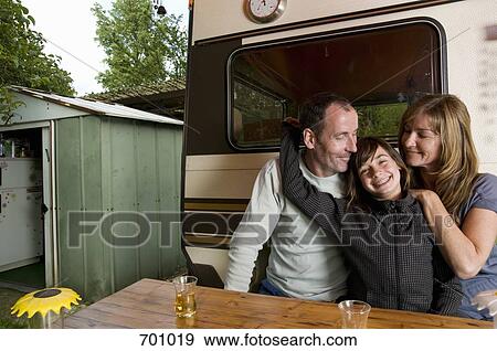 Stock Photo - A family sitting at a table outside of their caravan. Fotosearch