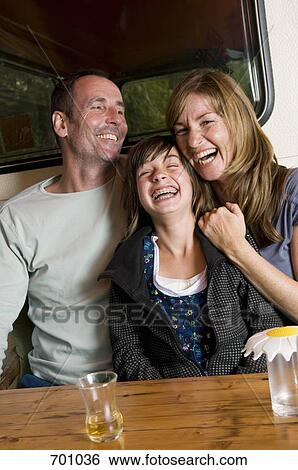 Stock Photograph - A family sitting at a table outside of their caravan. Fotosearch