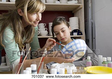 Stock Photo - A mother helps her daughter at a pottery studio. Fotosearch
