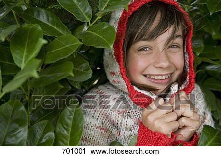 Stock Image - A young girl hiding in a bush. Fotosearch