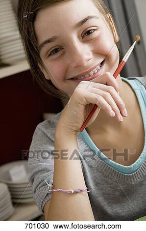 Stock Image - A young girl holding a paintbrush. Fotosearch