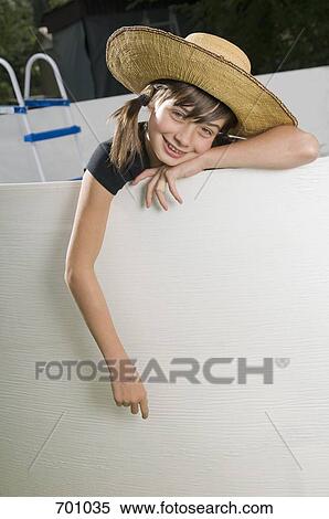 Stock Photography - A young girl leaning on the edge of an empty swimming pool. Fotosearch