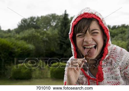 A young girl making a face while licking a lollipop View Large Photo Image Stock Image - A young girl making a face while licking a lollipop. Fotosearch