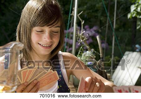 Stock Photograph - A young girl playing a card game, outdoors. Fotosearch